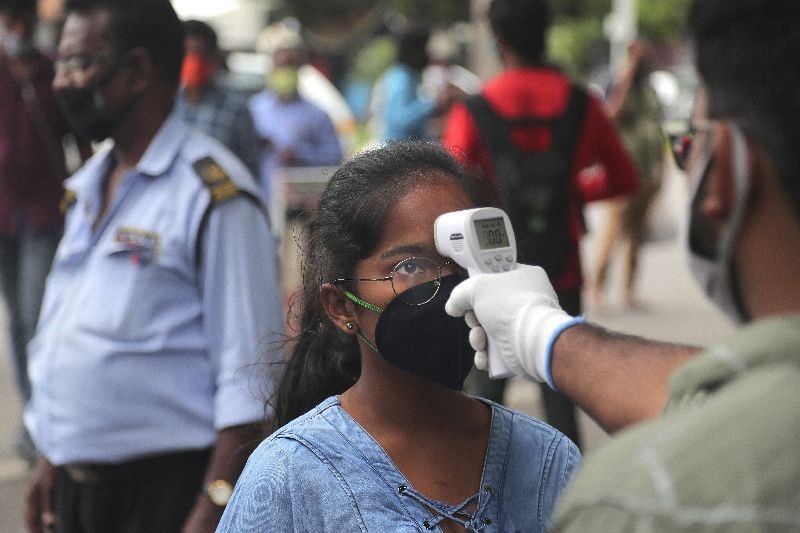 An official checks the body temperature of a candidate wearing a face mask as a precaution against coronavirus before appearing for National Eligibility cum Entrance Test ( NEET) at an exam centre in Hyderabad, India.  (Photo by Mahesh Kumar A./AP Photo)